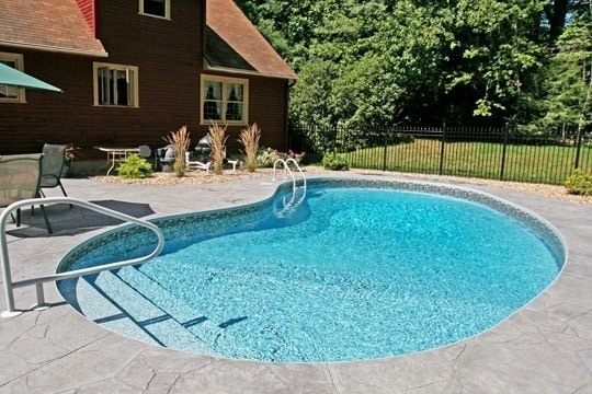 This is a photo of a custom kidney inground pool with black fence and stairs installed by Julianos