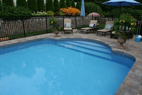 This Is A Photo Of A Patrician In Ground Pool In Cromwell, CT With Custom Pavers, Black Fence And Diving Board.