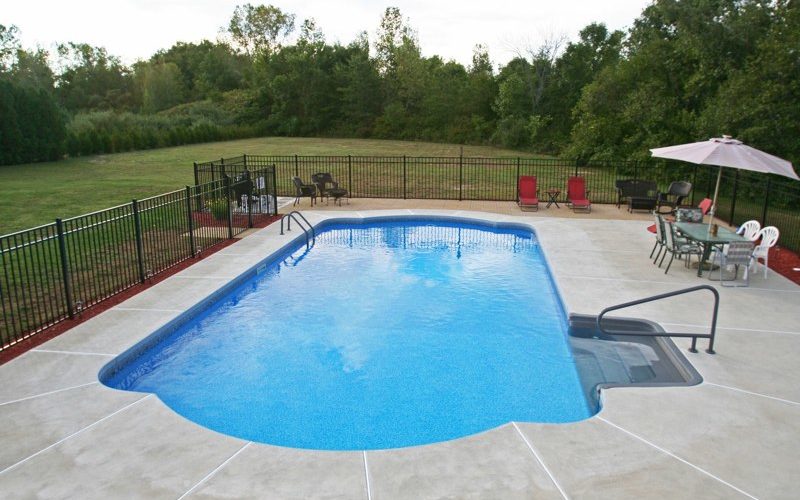 This Is A Photo Of A Roman In Ground Pool In Somers, CT With Custom Pavers, Black Fence And Steps.