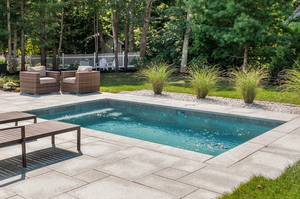 Inground outdoor Plunge Pool surrounded by oriental grass and lounge chairs
