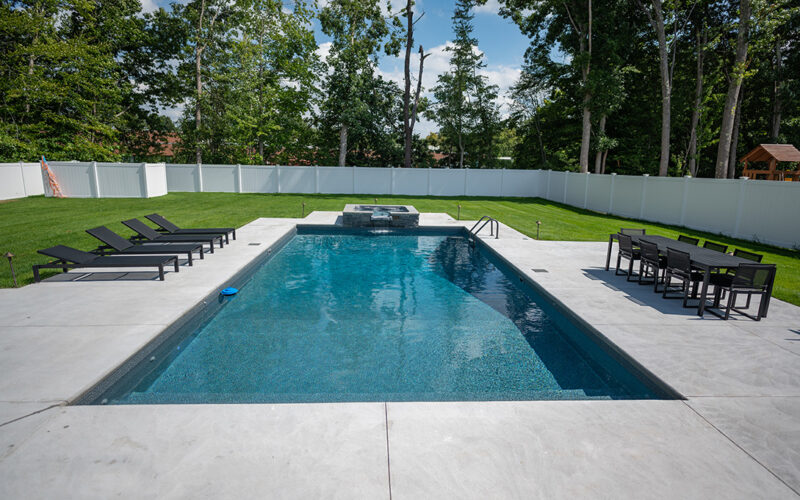 Inground Rectangular Swimming Pool With Overflow Spa And Cement Patio