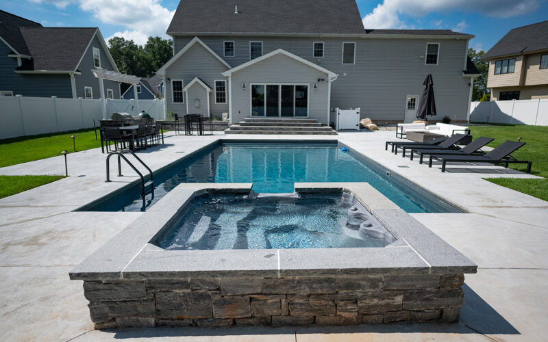 Inground Rectangular Swimming Pool With Overflow Spa And Cement Patio